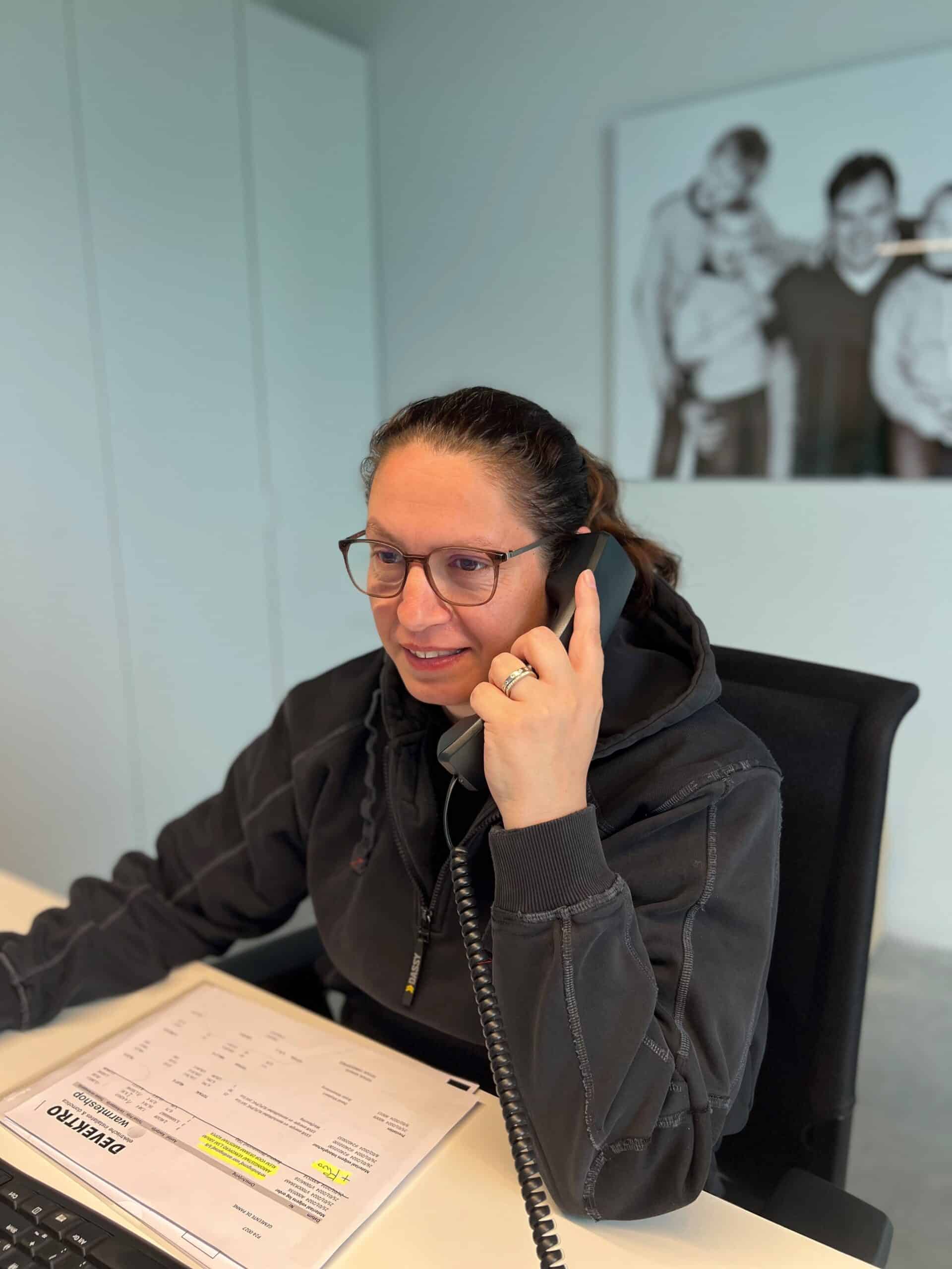 Administratief bediende dat aan haar bureau zit, aan het bellen met een klant