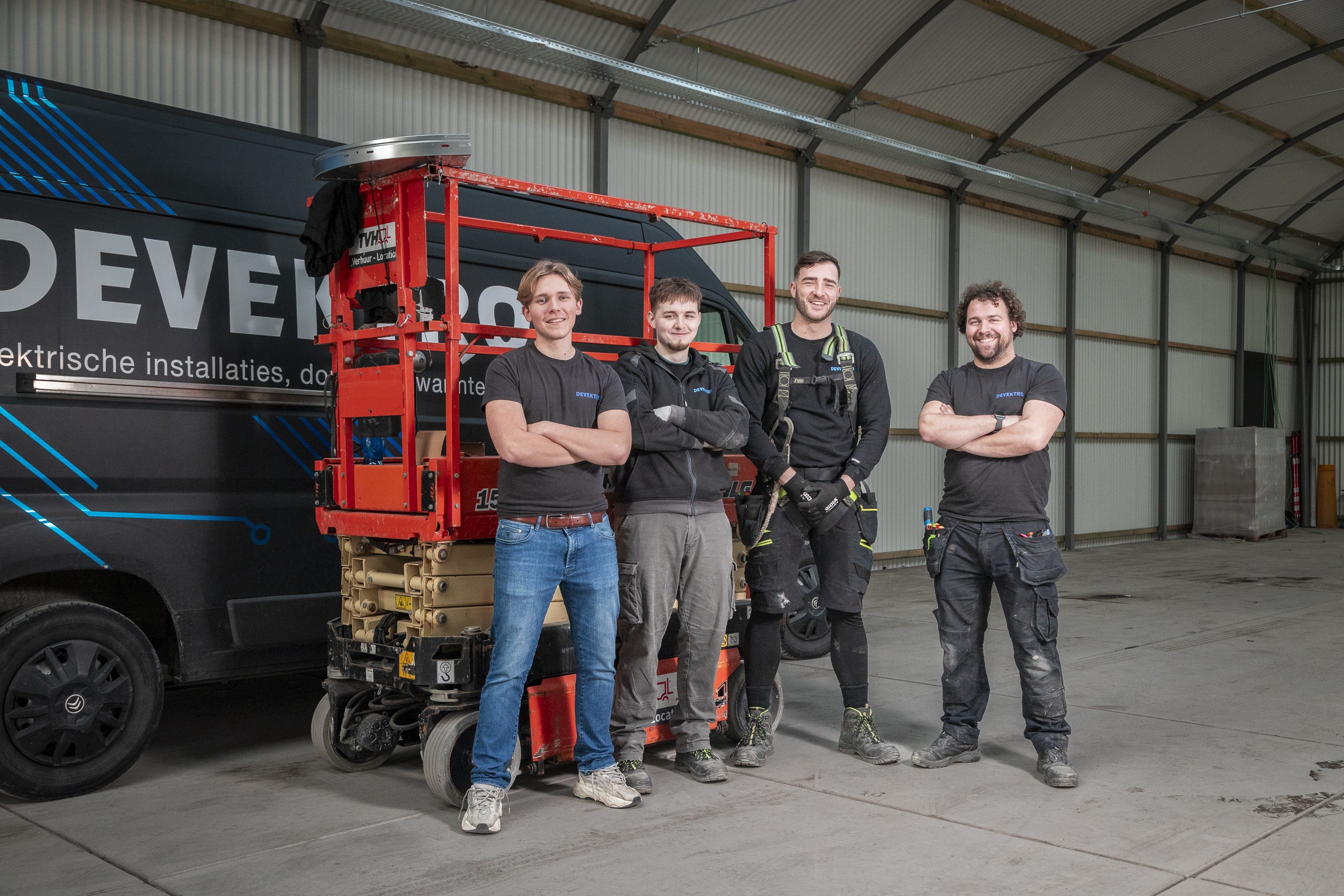 Vier elektriciens die voor een camionette staan, klaar om te werken.